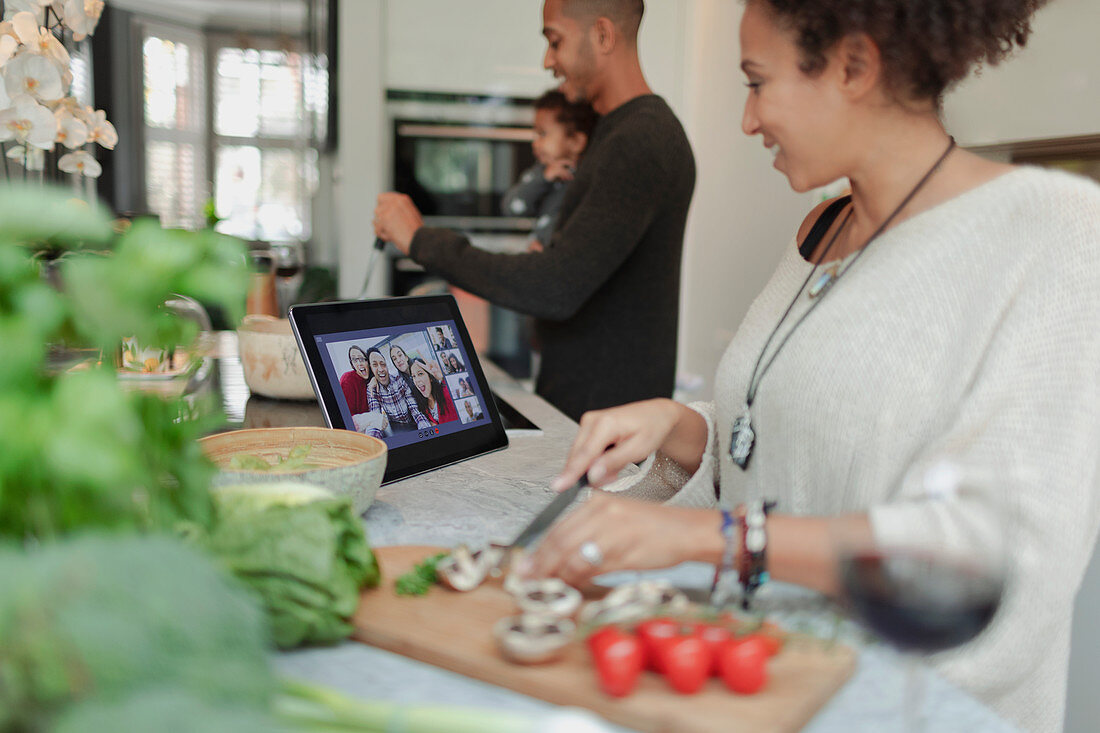 Family cooking and video chatting at digital tablet