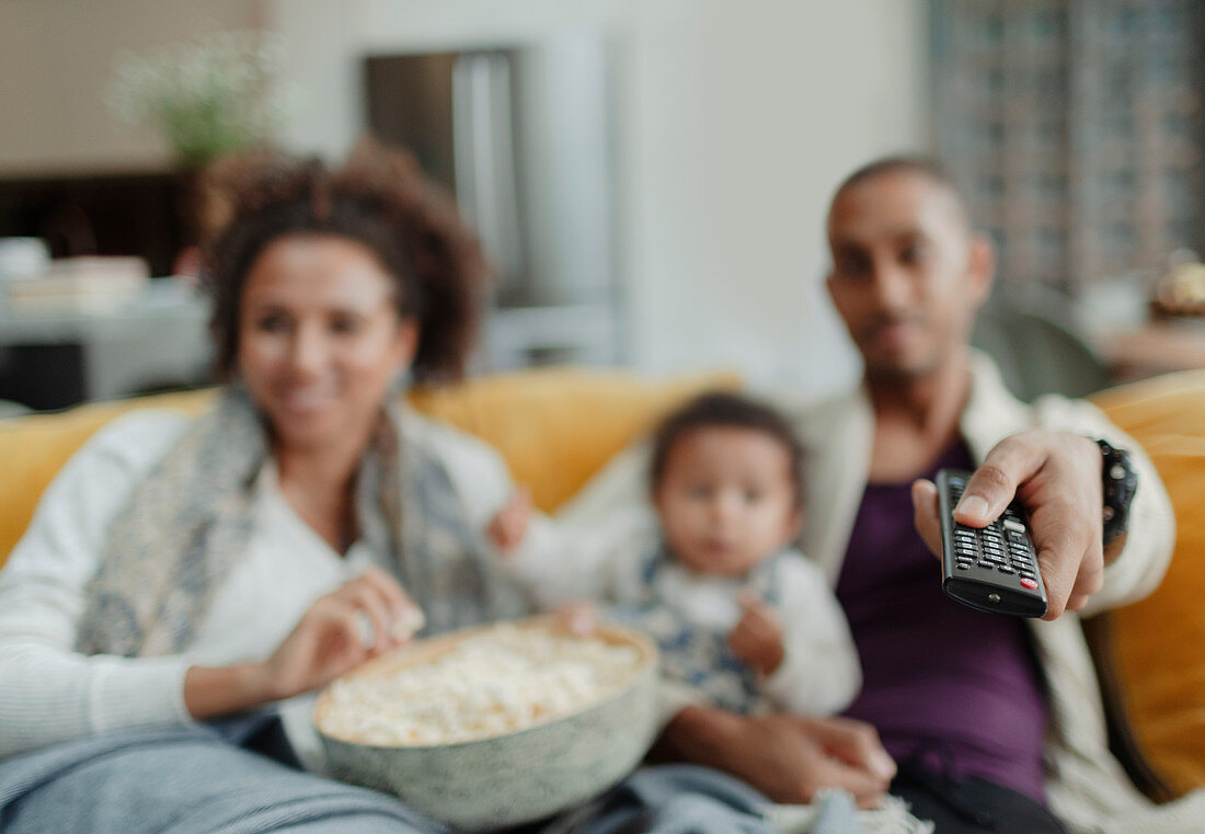 Family with remote control watching TV with popcorn