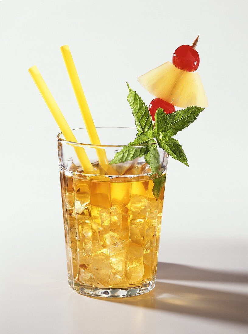 A glass of Mai Tai with yellow straw, mint