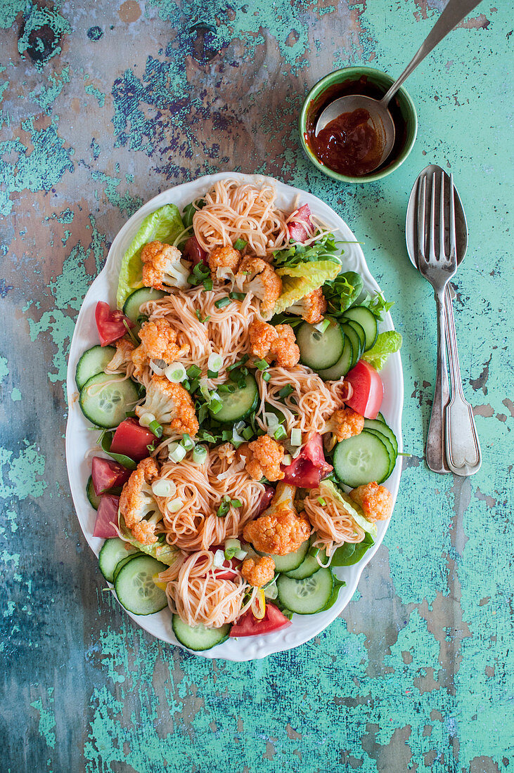 Vegan rice noodle salad with cauliflower, lettuce, cucumber, tomatoes and spring onion