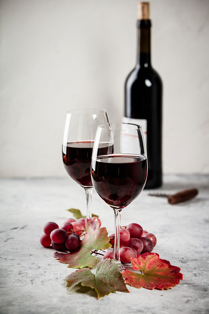 Zwei Gläser Rotwein, Trauben und Weinblätter