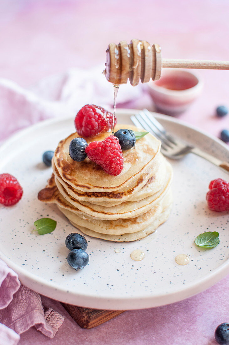 Pancakes mit Honig, Blaubeeren und Himbeeren