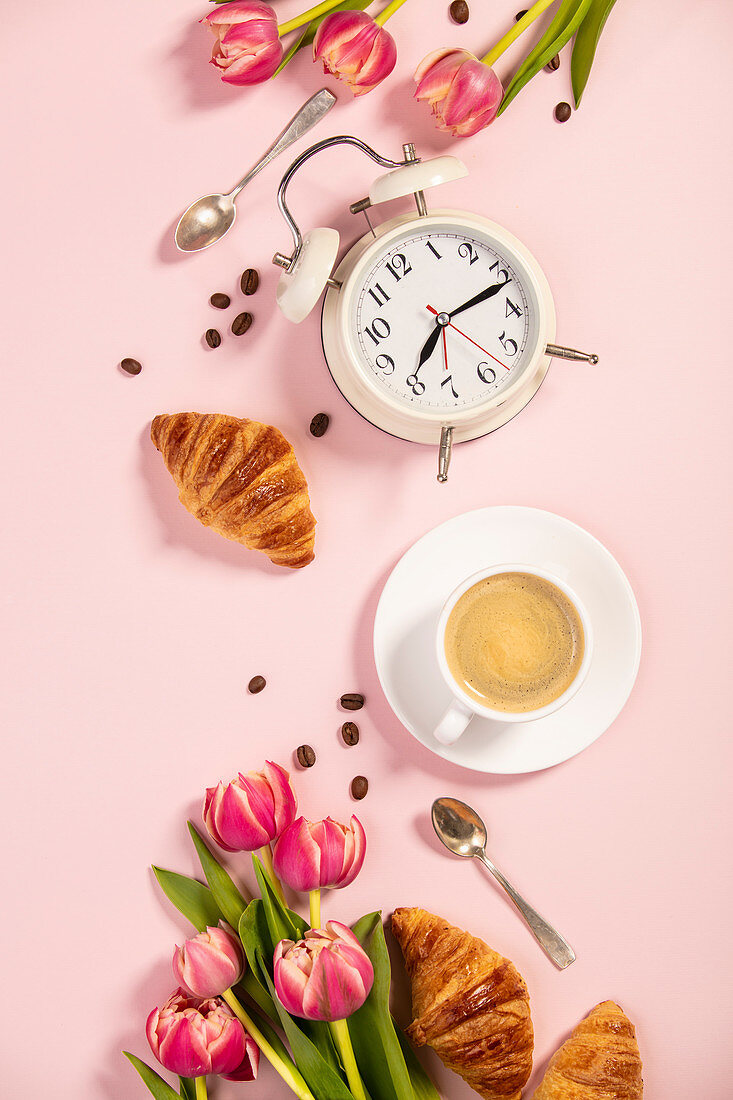 Morgenkaffee, Croissants, Wecker und Tulpen
