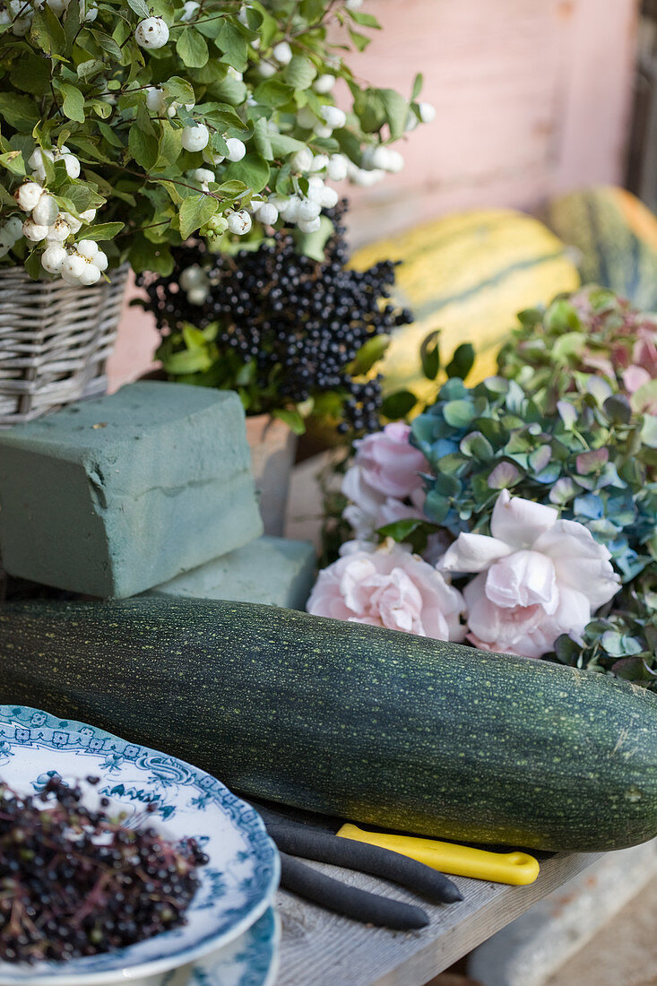 materials for autumn decorations: courgettes, privet berries, roses, hydrangea blossoms, snowberry, and damp sponge