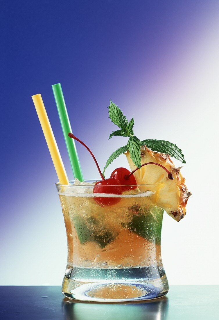 A glass of Mai Tai with straws; limes, pineapple, cherry