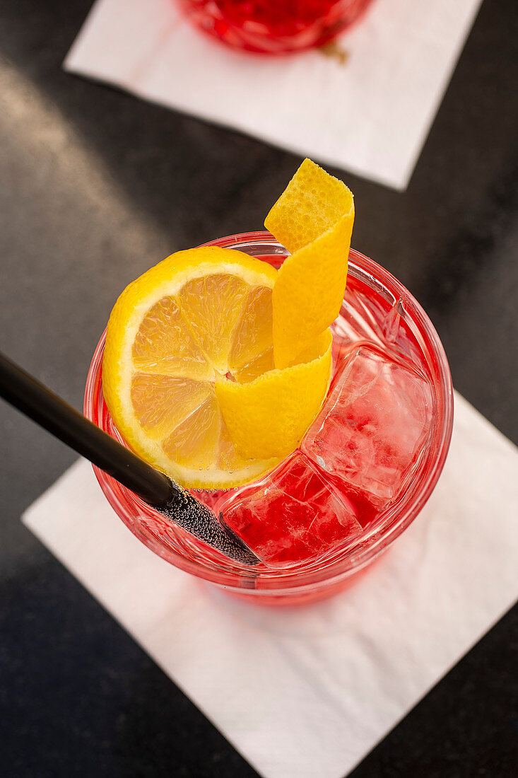 Campari soda with ice cubes and a lemon slice
