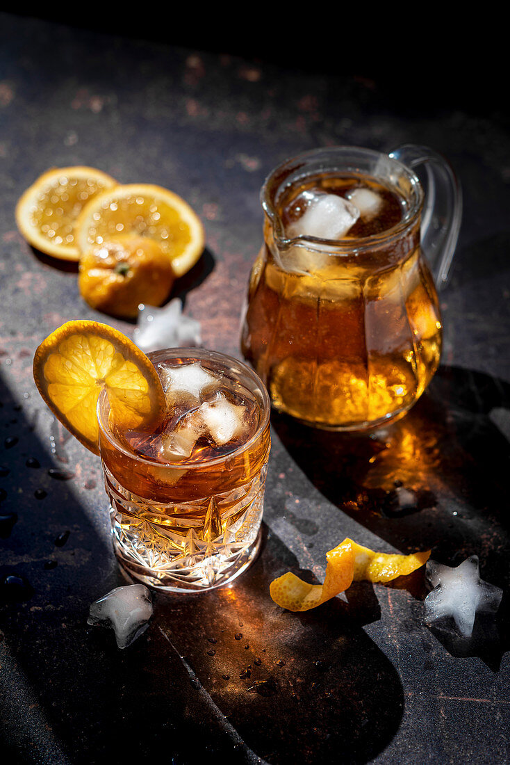 Glass of cold orange drink with ice cubes and orange slices