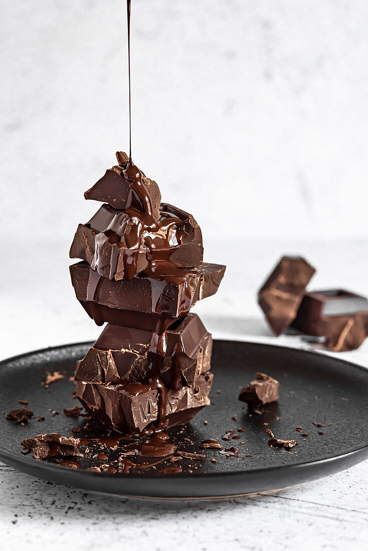 Schokoladensauce tropft auf Stapel von Schokoladenstücken