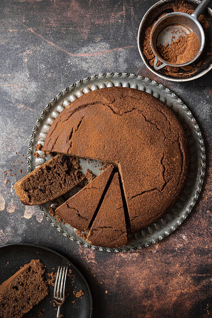 Schokoladenkuchen mit Sieb und Kakaopulver
