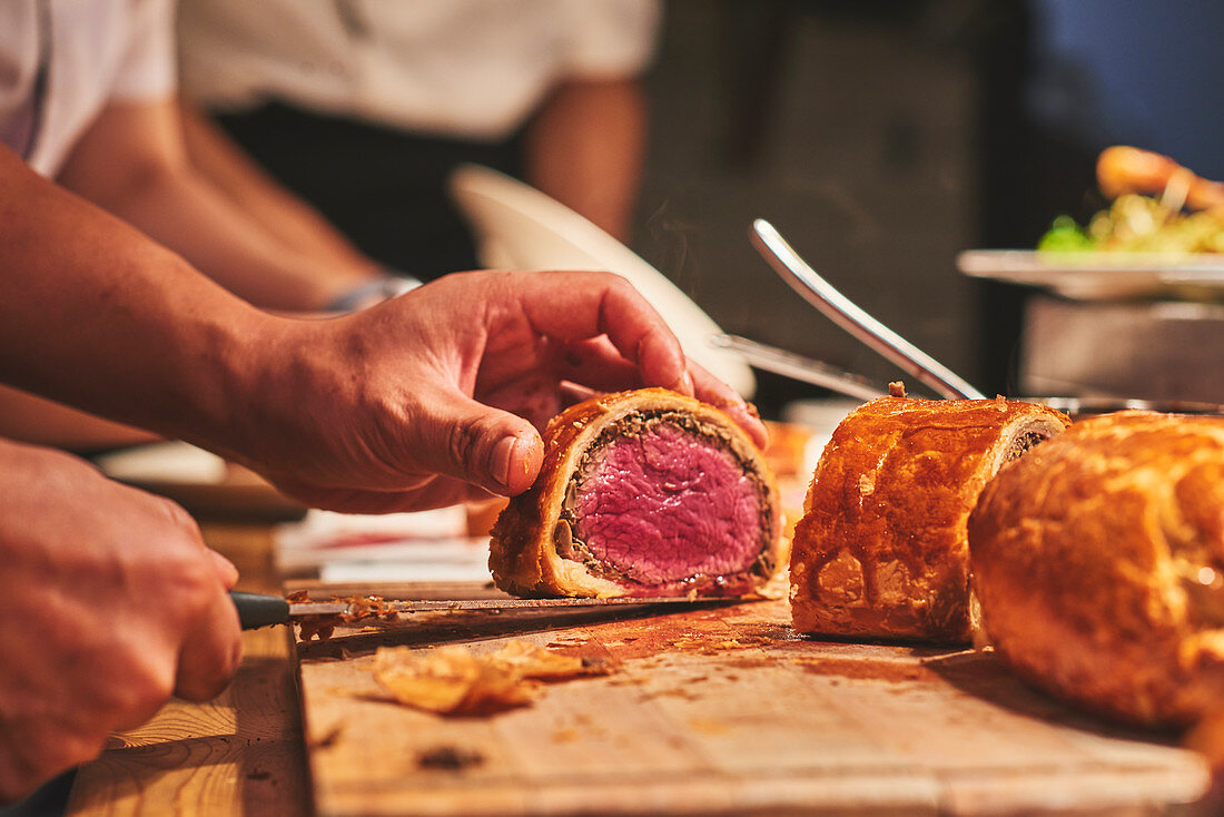 Köche portionieren Filet Wellington in französischem Restaurant