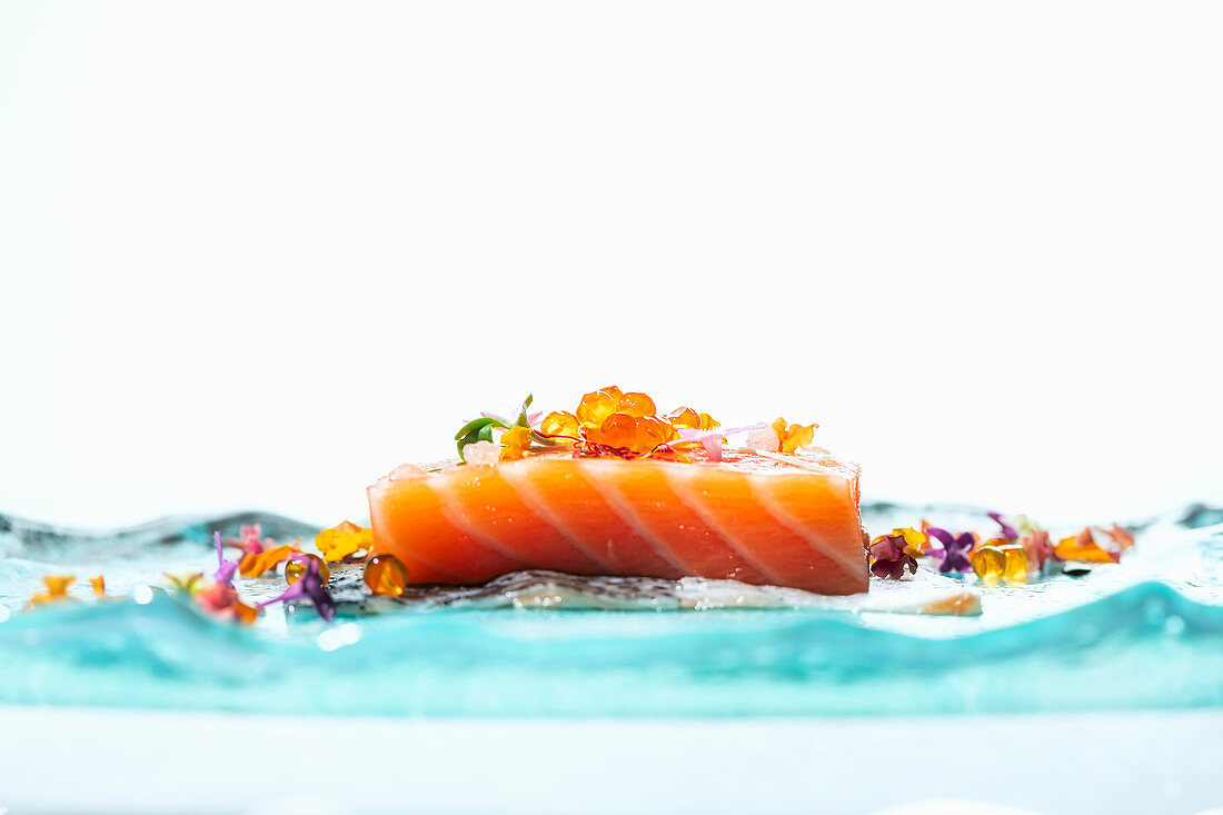 Raw salmon fillet decorated with flowers and caviar