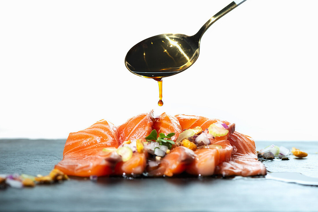Spoon of soy sauce over raw salmon fillet