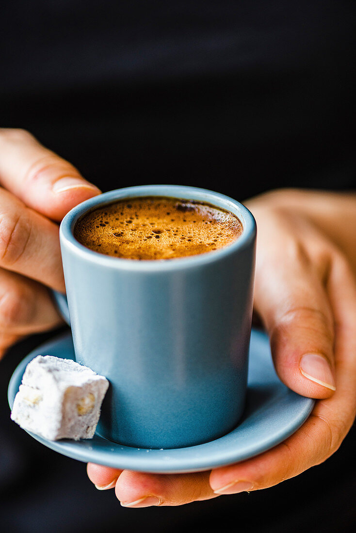 Hände halten türkischen Kaffee mit Lokum