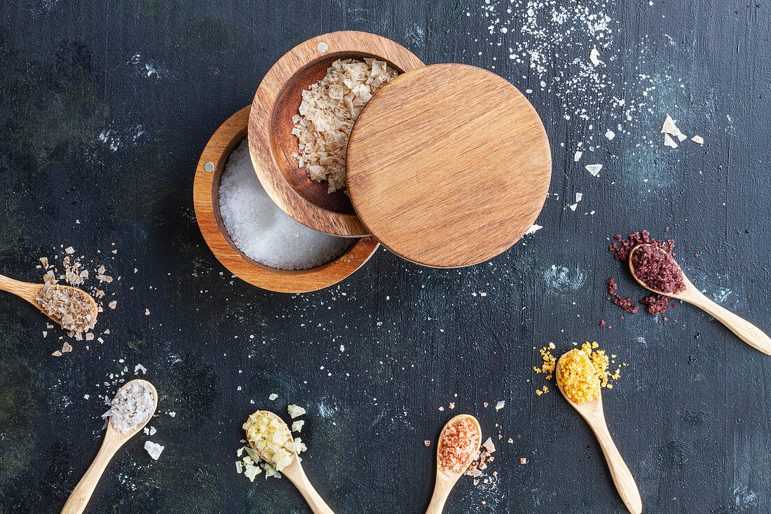 Various types of salt in wooden jars and spoons