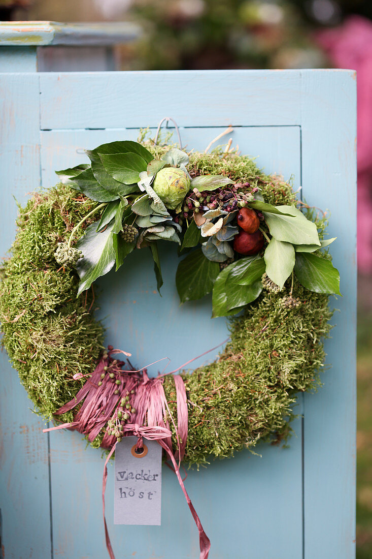 Door wreath of moss with ivy, hydrangea blossoms, and Brussels sprouts
