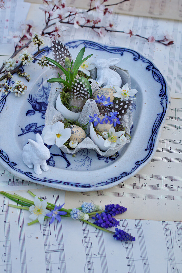 Small Easter arrangement with Easter bunny, various flowers, grape hyacinths and feathers in egg box