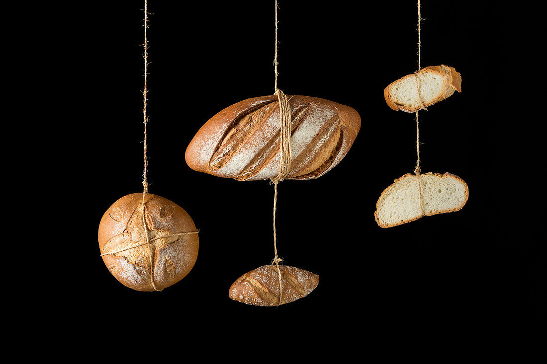 Loafs and pieces of artisan bread hanging on ropes