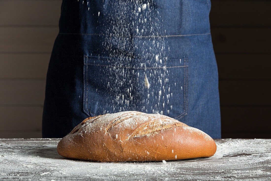 Sprinkling flour over bread loaf