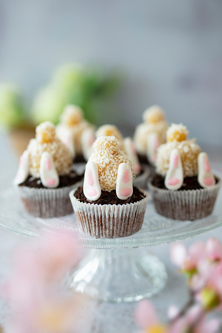 Muffins with upside down Easter bunnies made of marzipan, biscuit and fondant