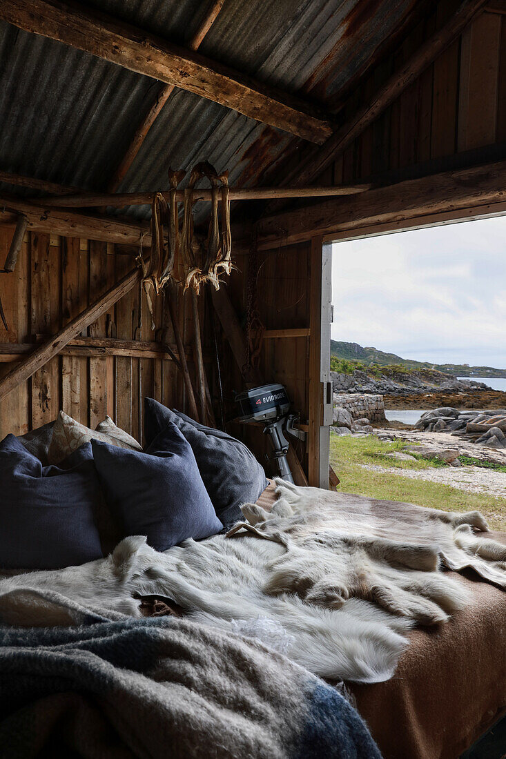 Pillows and fur blankets on bed in rustic wooden shed