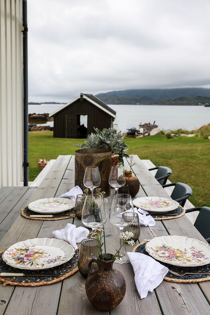 Gedeckter Holztisch mit Stühlen auf der Terrasse mit Blick auf die Lofoten