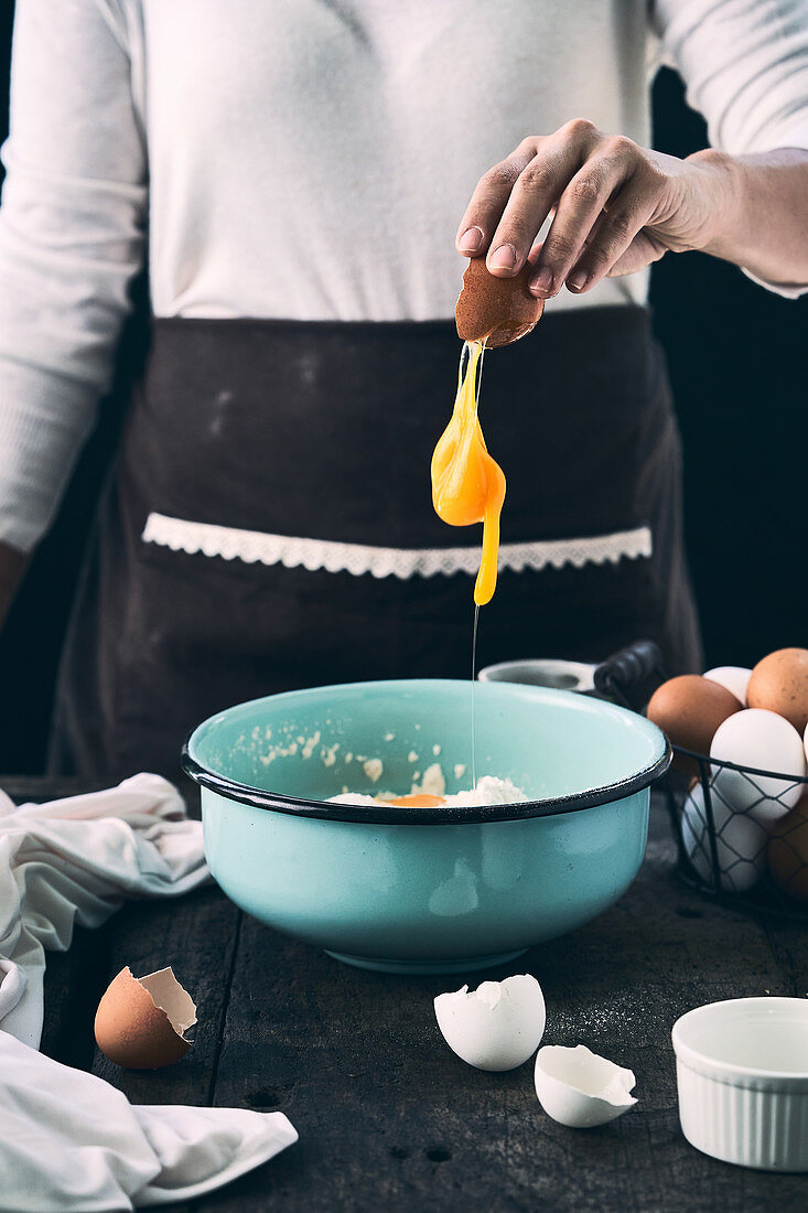 Woman adding egg in bowl