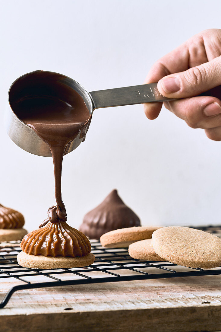 Pouring chocolate cream on cookies with caramel