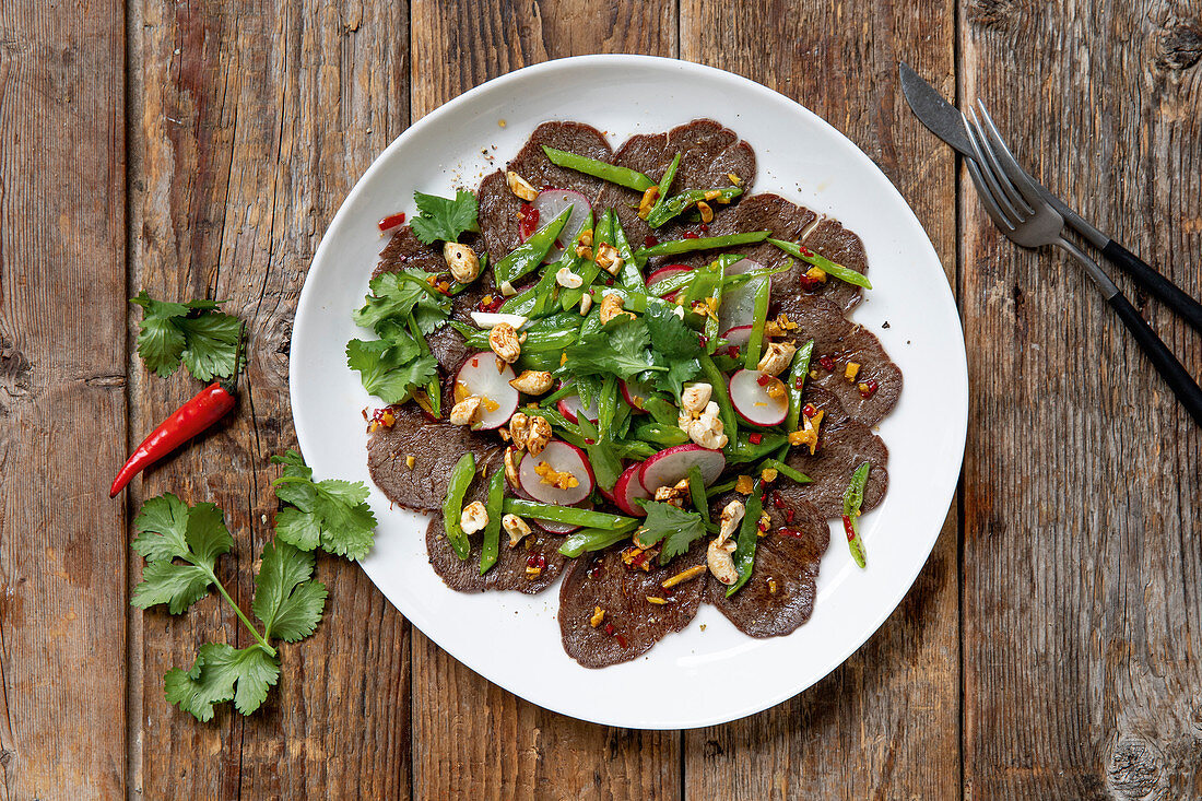 Marinated beef fillet with radish, pea pods and nuts