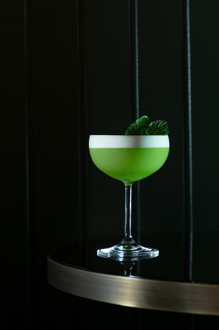 Green cocktail garnished with mint leaves