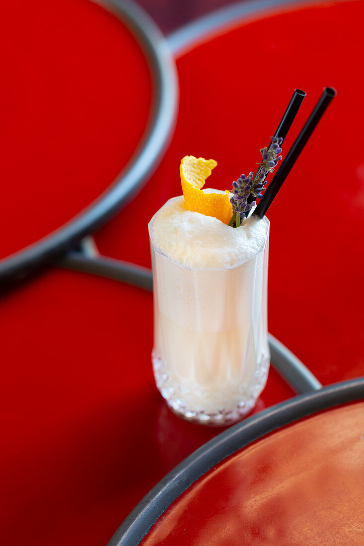 Creamy cocktail garnished with orange peel and lavender flower