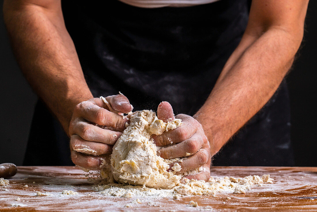 Hands kneading and rolling pile of dough for bread