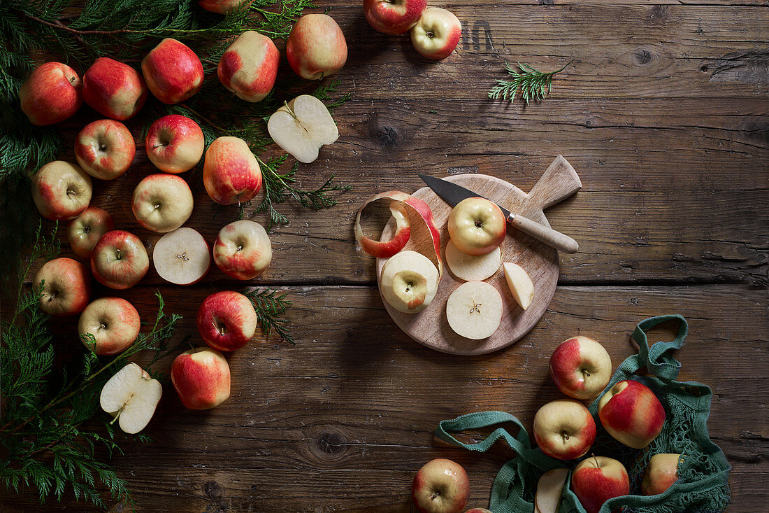 Whole and sliced red apples with cutting board and knife