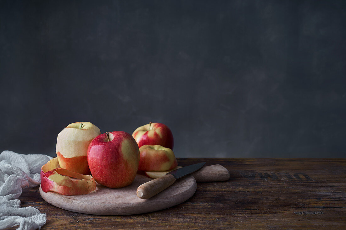 Whole and sliced red apples with cutting board and knife