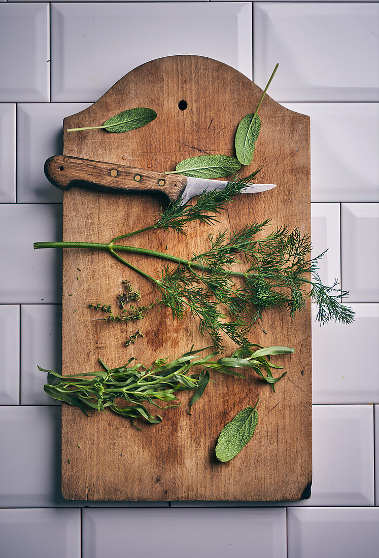 Sage, dill, tarragon and thyme on a wooden board