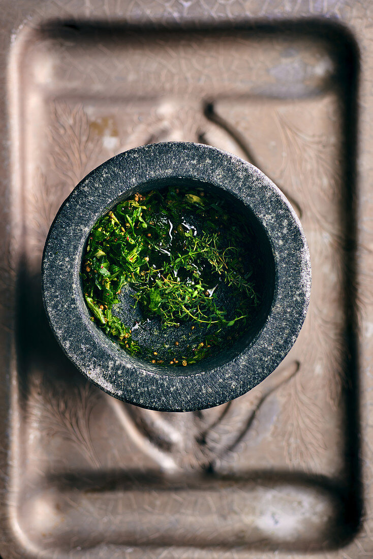 Fresh herbs and spices for chimichurri in a mortar