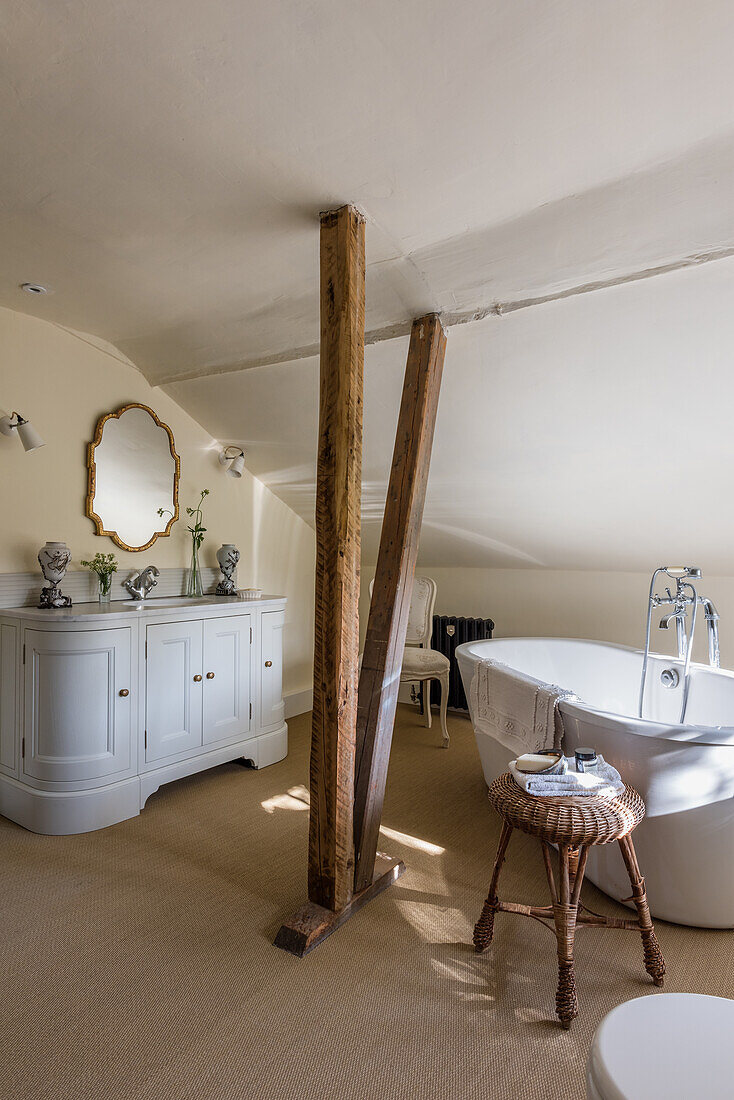 Renovated bathroom with freestanding bathtub, washstand and rustic wooden posts