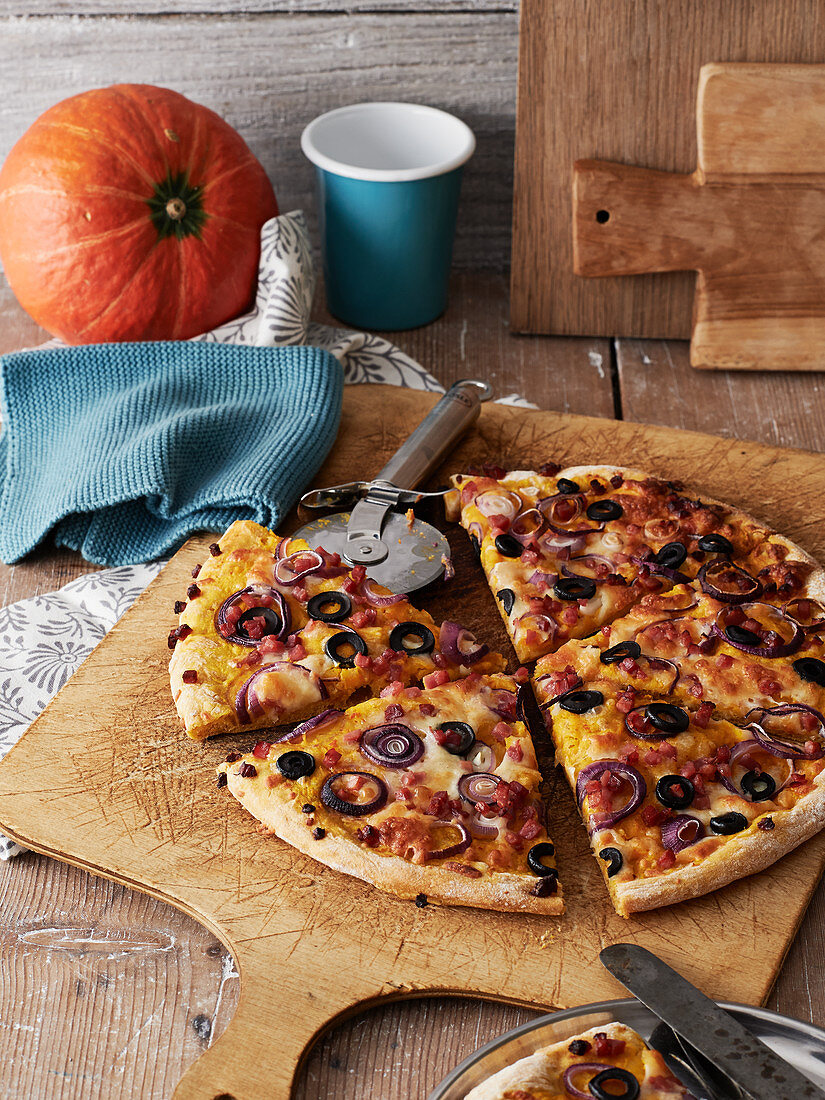 Pumpkin pizza with bacon, olives and red onions