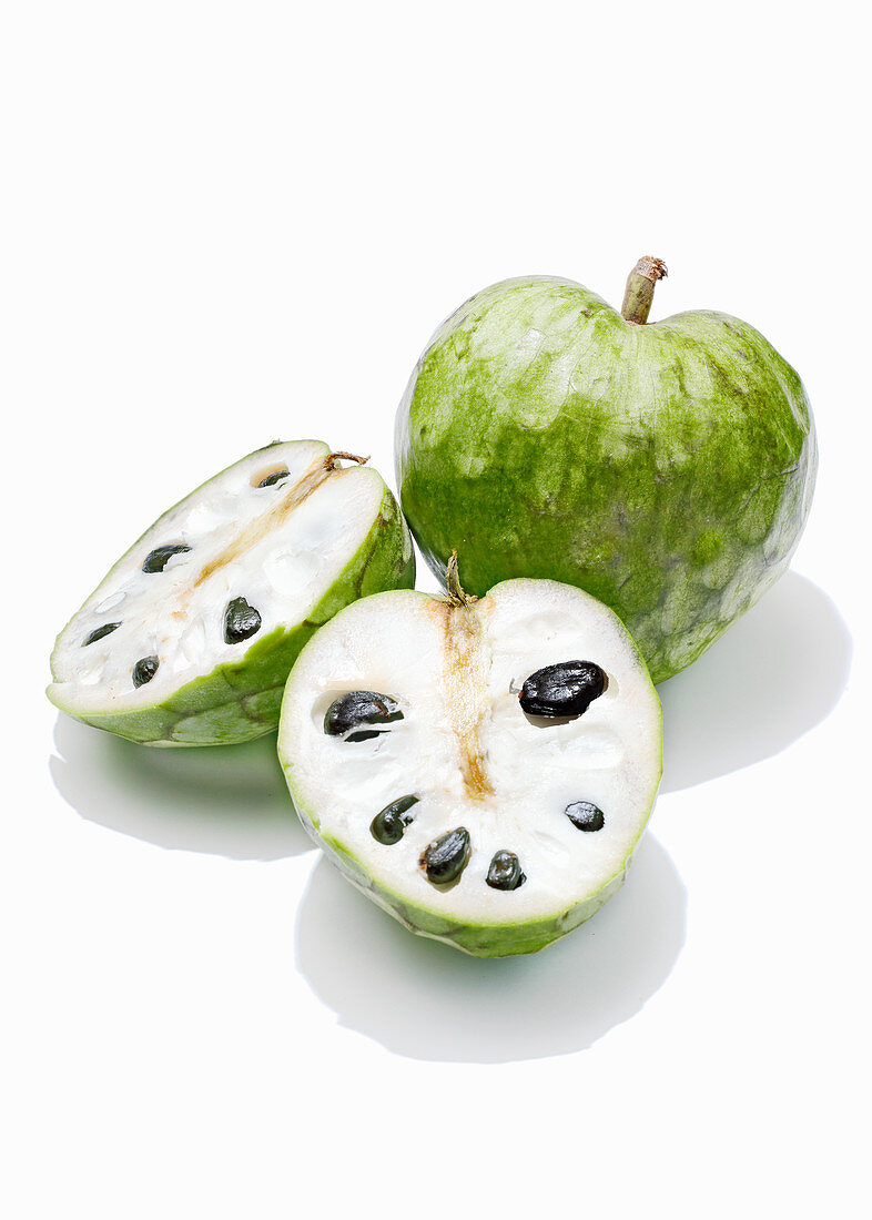 Cherimoya, ganz und halbiert vor weißem Hintergrund