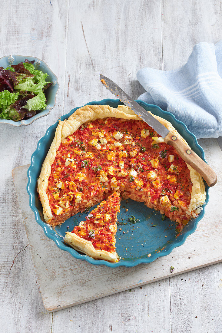 Spicy rice quiche with cheese in a pie dish, sliced