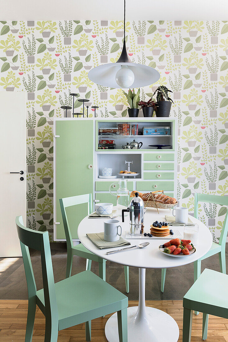 White table with green chairs and vintage sideboard