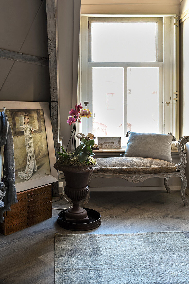 Amphore mit Orchideen und Polsterbank vorm Fenster im Altbau