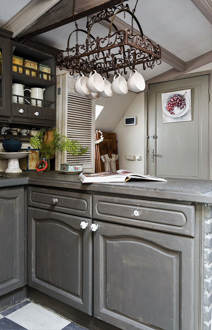 Cups hung from storage rack in grey, vintage-style kitchen