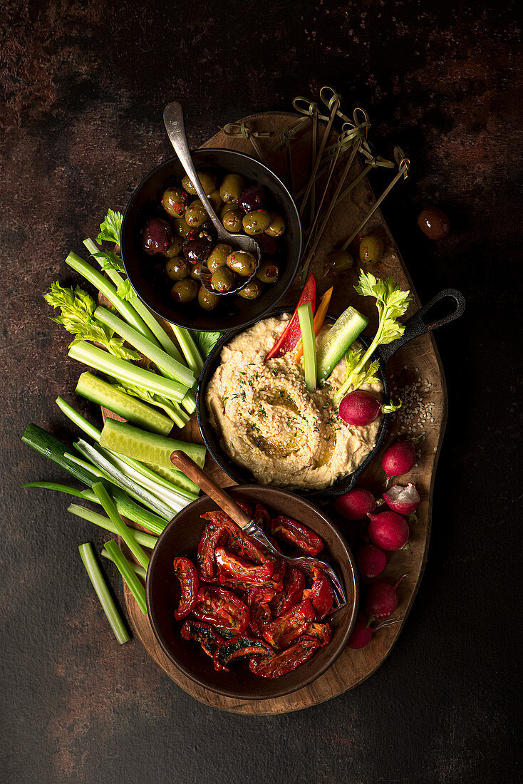 Rohkostplatte mit Hummus, Oliven und getrockneten Tomaten