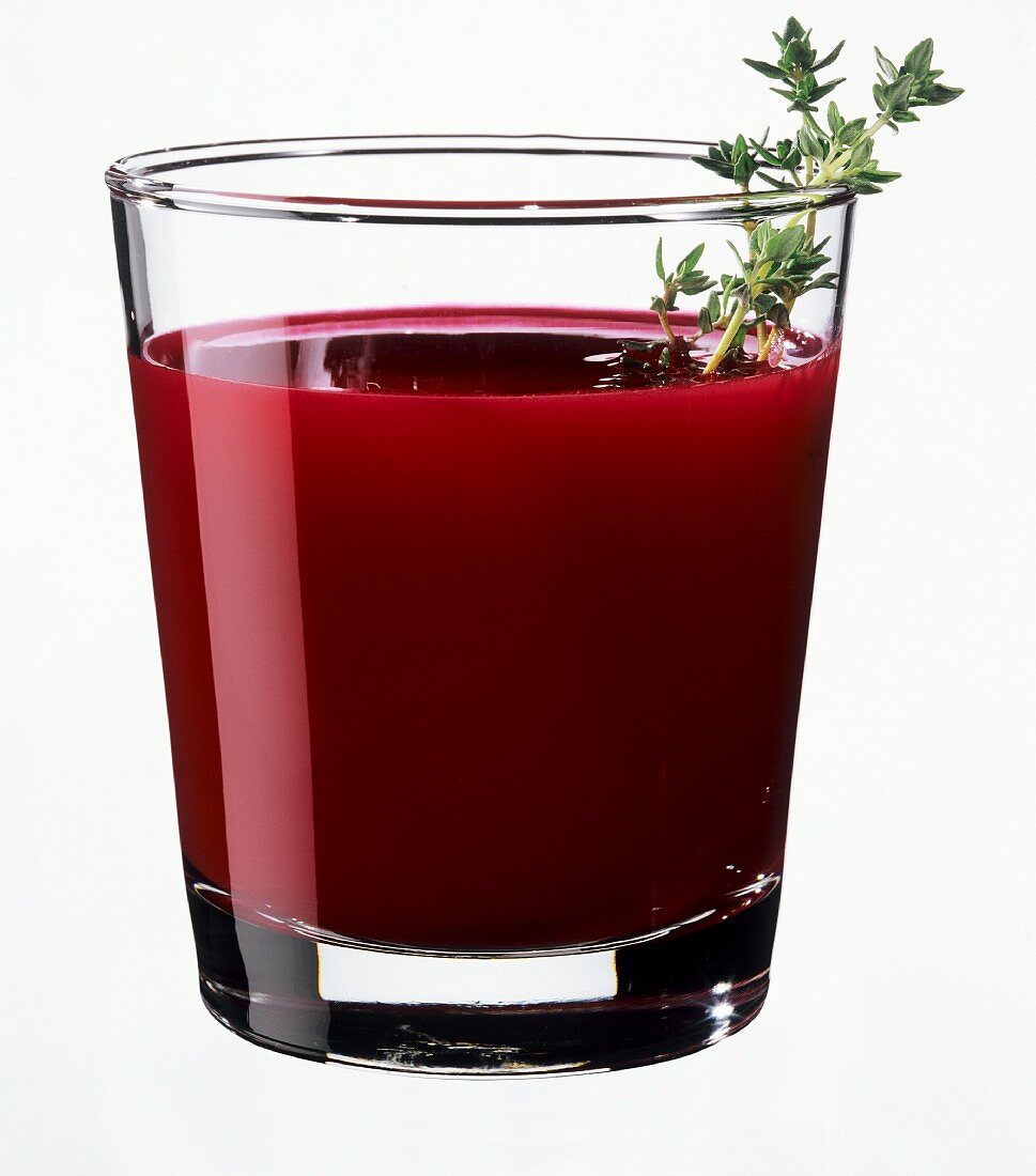 A glass of beetroot juice garnished with thyme sprig 