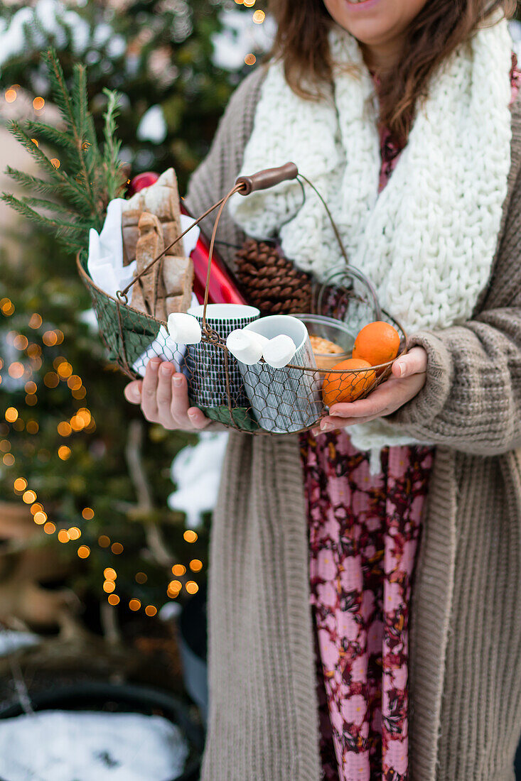 Frau hält Drahtkorb mit Zubehör für Winterpicknick