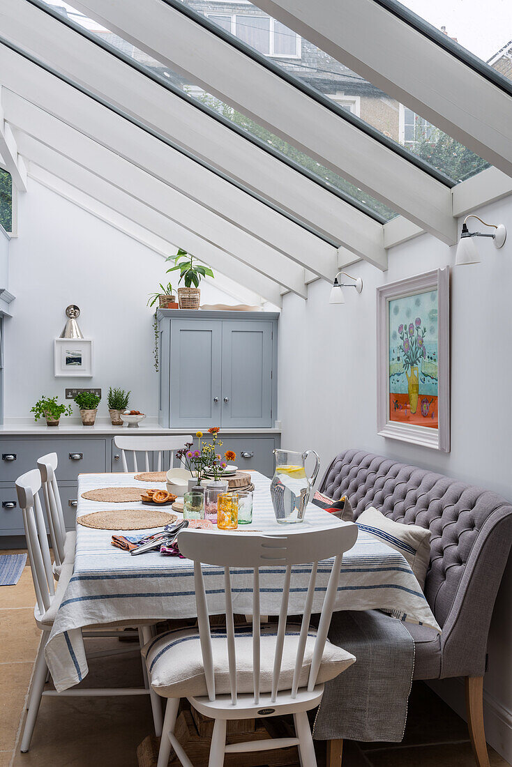 Dining table with chairs and upholstered bench under glass roof