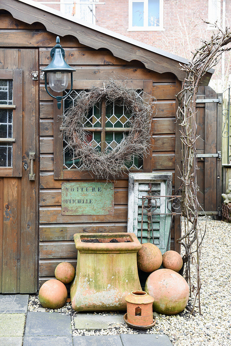 Kranz, Blumenkübel und Terracottakugeln am Gartenhaus