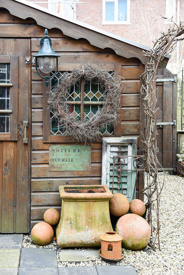 Wreath, planter and terracotta balls outside garden shed