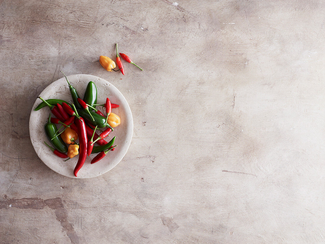 Varieties of chili on plate on stone surface