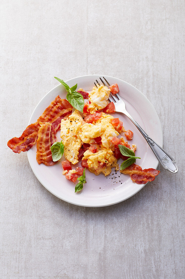 Scrambled eggs with tomatoes and crispy bacon